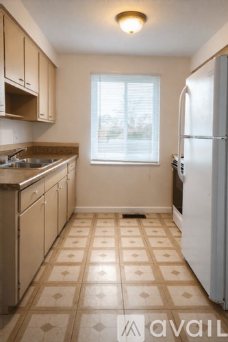 A kitchen with a tile floor and a refrigerator.