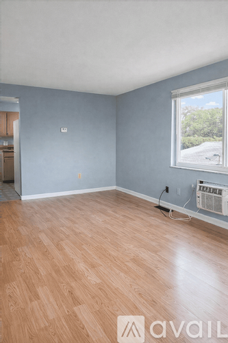 A room with wooden flooring and a window overlooking a street.