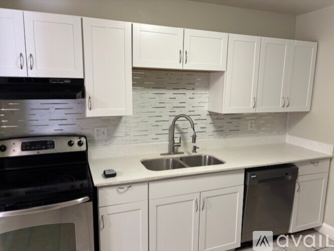 A kitchen with white cabinets and a black stove top oven.