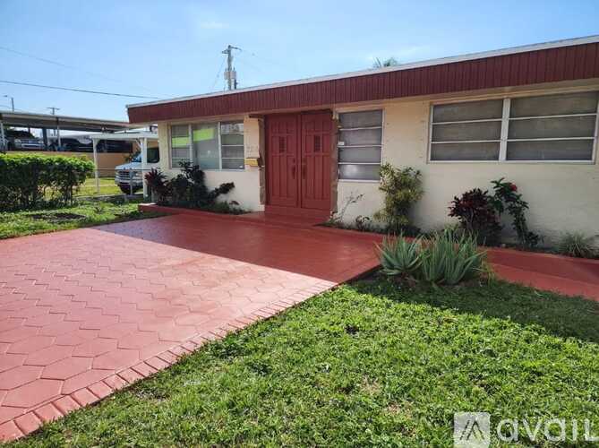 A red door is on the right side of a white building.