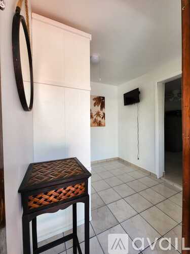 A small table with a woven top is in a room with a white door.