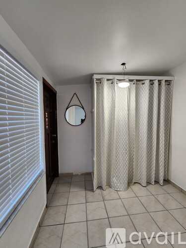 A bathroom with a shower curtain and a round mirror hanging on the wall.