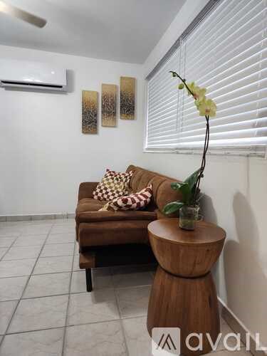 A living room with a brown couch and a wooden stool.