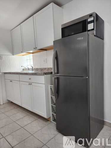 A kitchen with a stainless steel refrigerator and white cabinets.