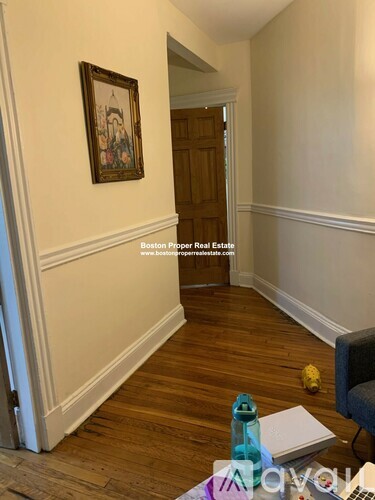 A hallway with a wooden floor and a painting on the wall.