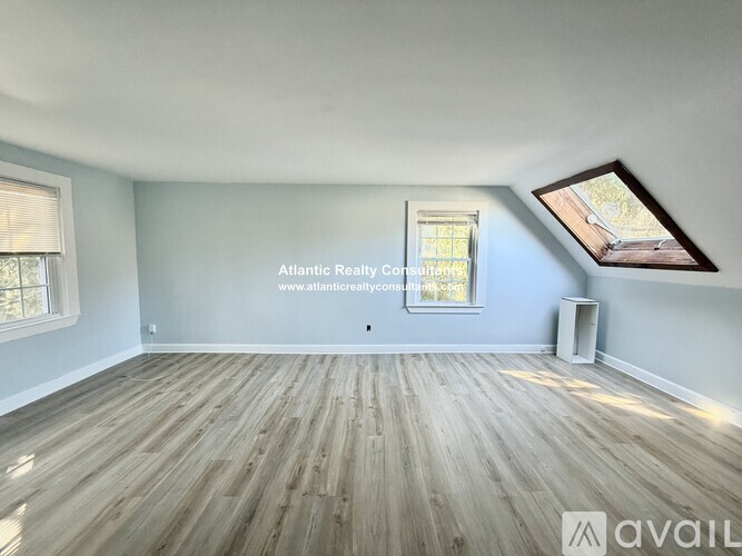 A spacious room with wooden flooring and a window.