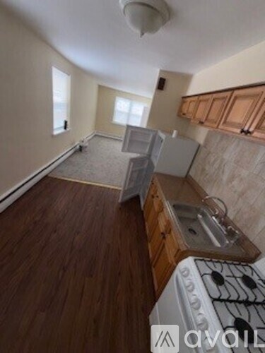 A kitchen with a white stove top oven and wooden cabinets.