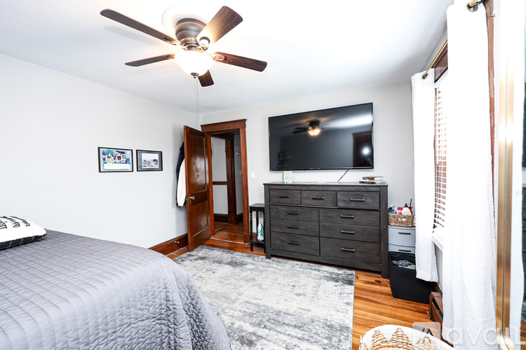 A bedroom with a bed, dresser, and television.