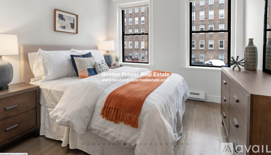 A bedroom with a bed, nightstands, and a window overlooking a cityscape.