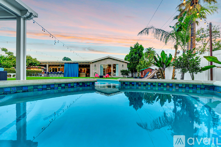 A house with a pool in front of it is available for sale.