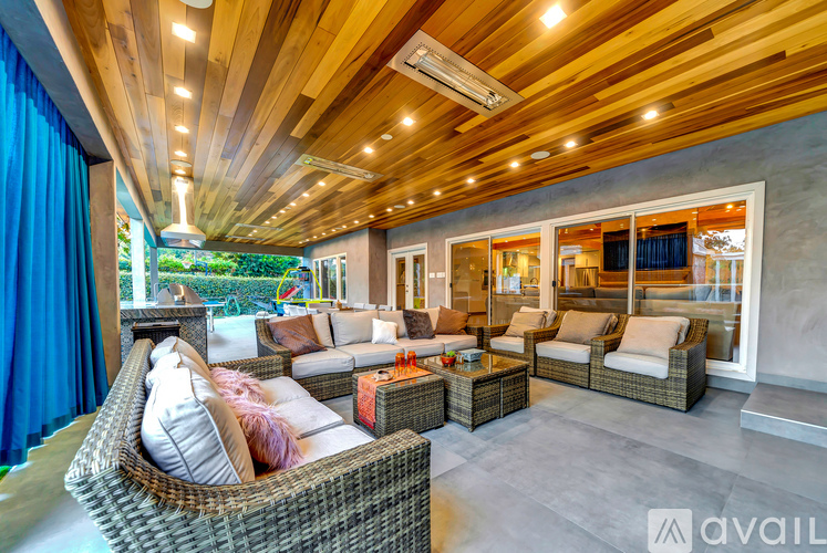 A modern outdoor living space with a wicker sofa and a wooden ceiling.