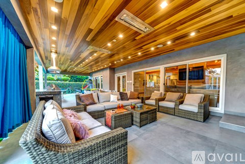 A modern outdoor living space with a wicker sofa and a wooden ceiling.