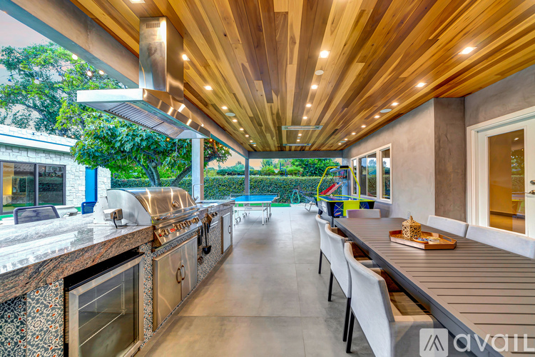 A modern kitchen with a wooden ceiling and a dining table set for four.