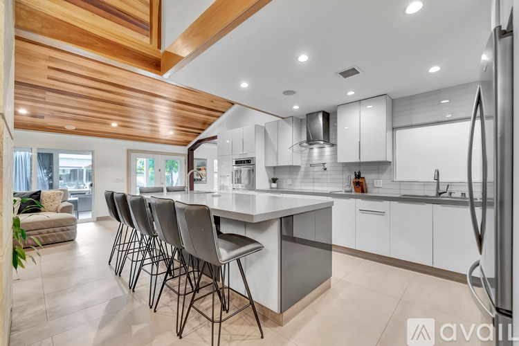 A modern kitchen with a wooden ceiling and white cabinets.