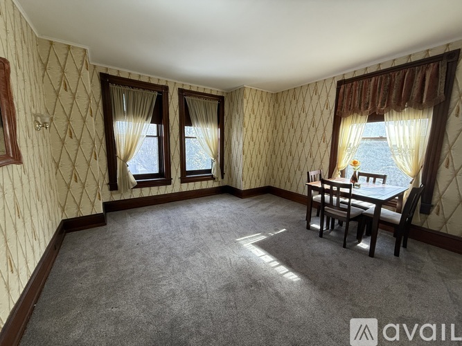 A room with a table and chairs and a window with curtains.