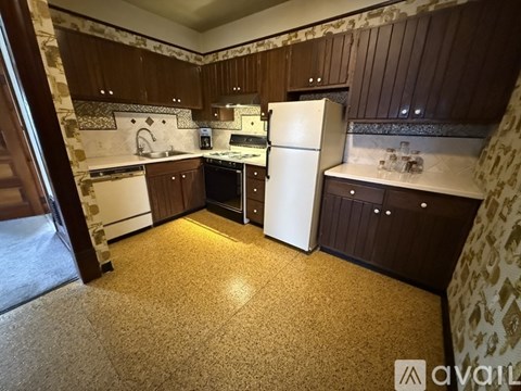 A kitchen with brown cabinets and a white refrigerator.