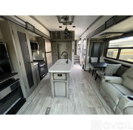 The image shows a well-equipped kitchen area in a vehicle with a sink, stove, and refrigerator.