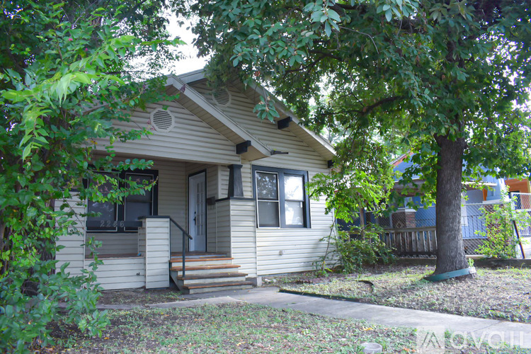 A small house with a front porch and a tree in front.