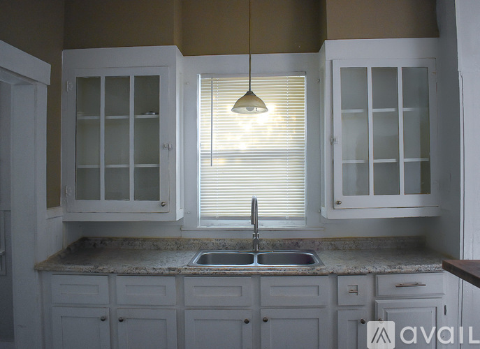 A kitchen with white cabinets and a sink under a window.