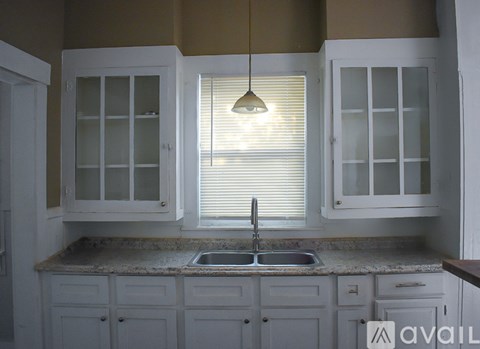 A kitchen with white cabinets and a sink under a window.