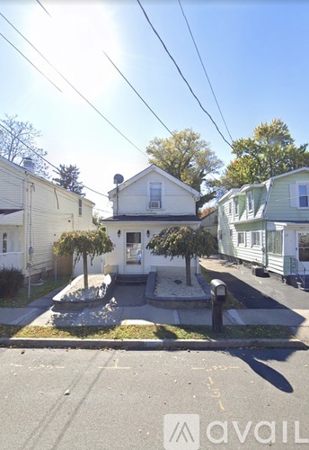A house with a front yard and a tree in front of it.