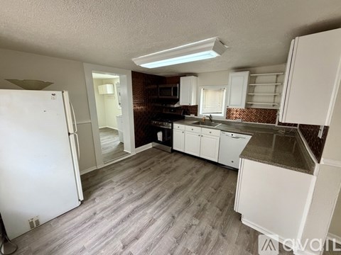 A kitchen with white cabinets and a white fridge.