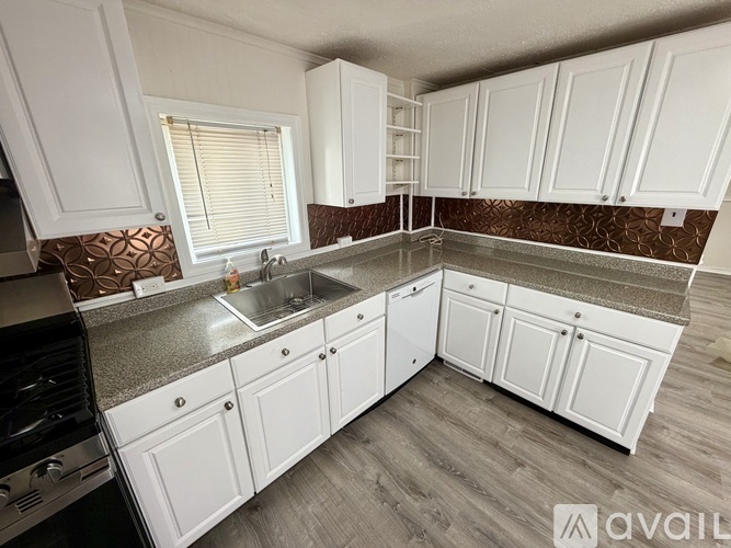 A kitchen with white cabinets and a stainless steel sink.