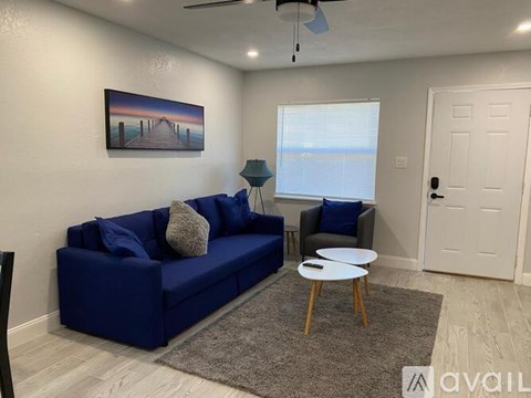 A living room with a blue couch, a small table, and a painting on the wall.