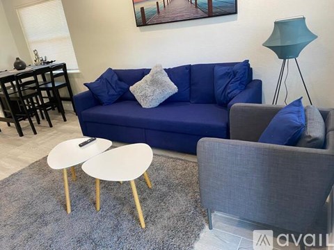 A living room with a blue couch, a grey armchair, and a white coffee table.