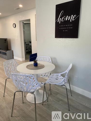 A white table and chairs are set up in a room with a sign that says "home" on the wall.