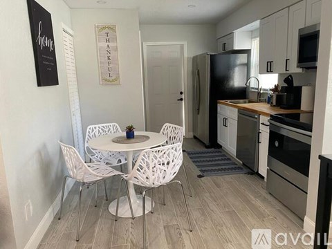 A kitchen with a table and chairs in the foreground and a refrigerator in the background.