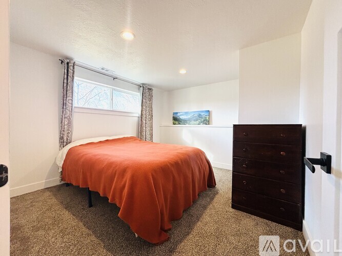 A bedroom with a bed, dresser, and window.