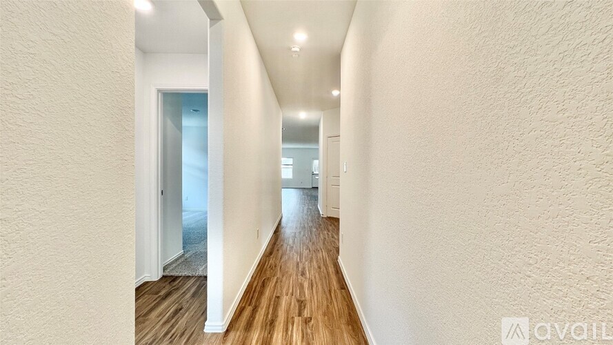 A long hallway with wooden floors and white walls.