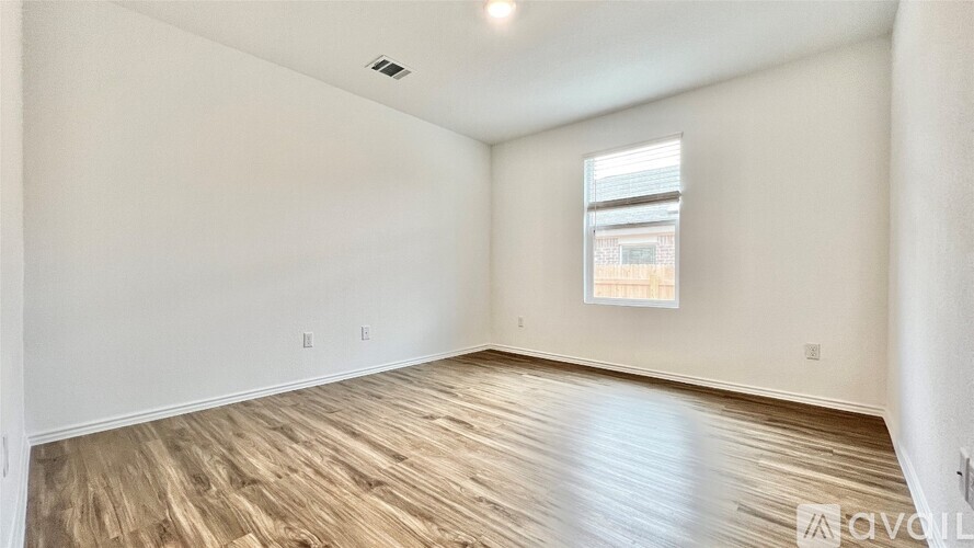 A spacious room with wooden flooring and a window.