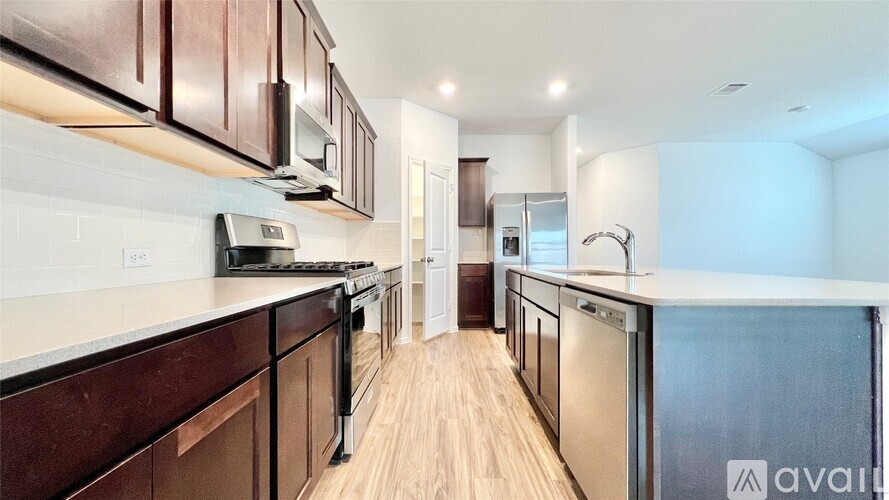 A kitchen with dark brown cabinets and stainless steel appliances.