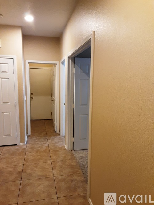 A hallway with a tiled floor and white doors.