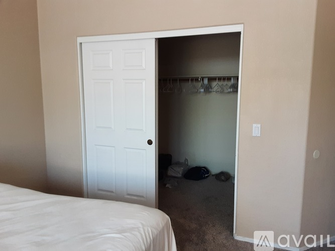A bedroom with a white bed and a white door leading to a hallway.