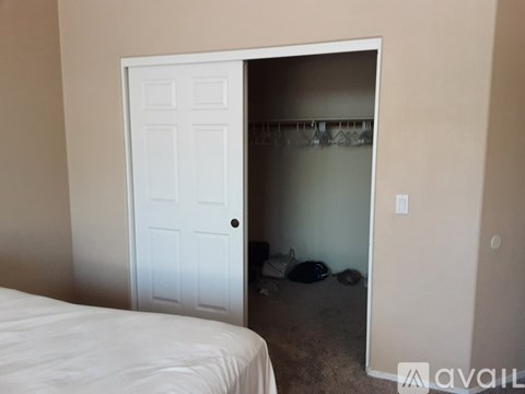 A bedroom with a white bed and a white door leading to a hallway.