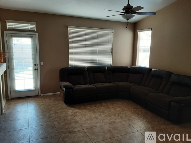 A black sectional sofa in a room with a ceiling fan.