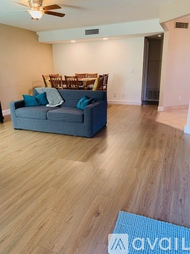 A living room with a grey couch and a wooden floor.