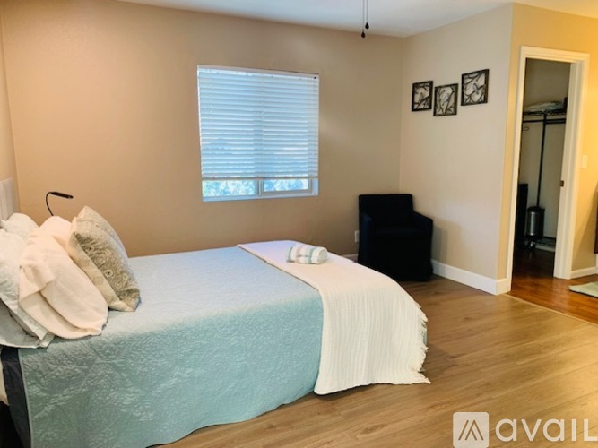 A bedroom with a bed, pillows, and a window with blinds.