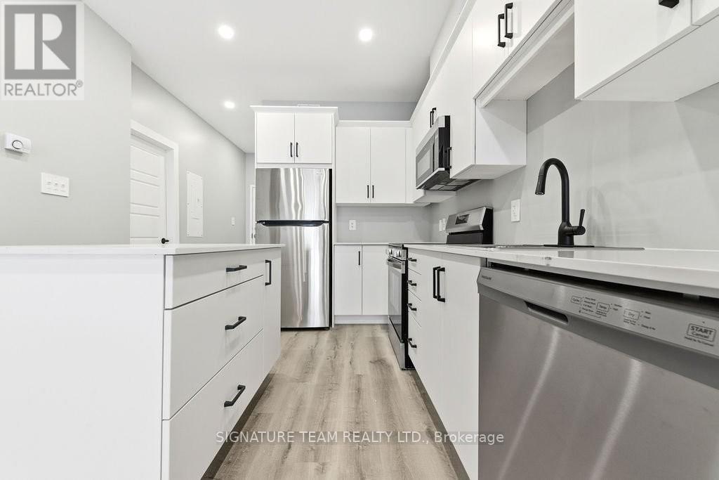 A modern kitchen with white cabinets and stainless steel appliances.