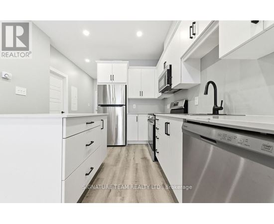 A modern kitchen with white cabinets and stainless steel appliances.