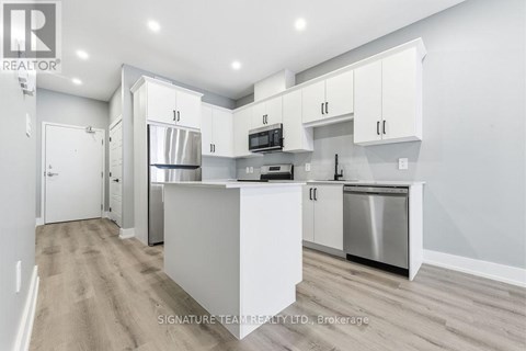 A modern kitchen with white cabinets and stainless steel appliances.