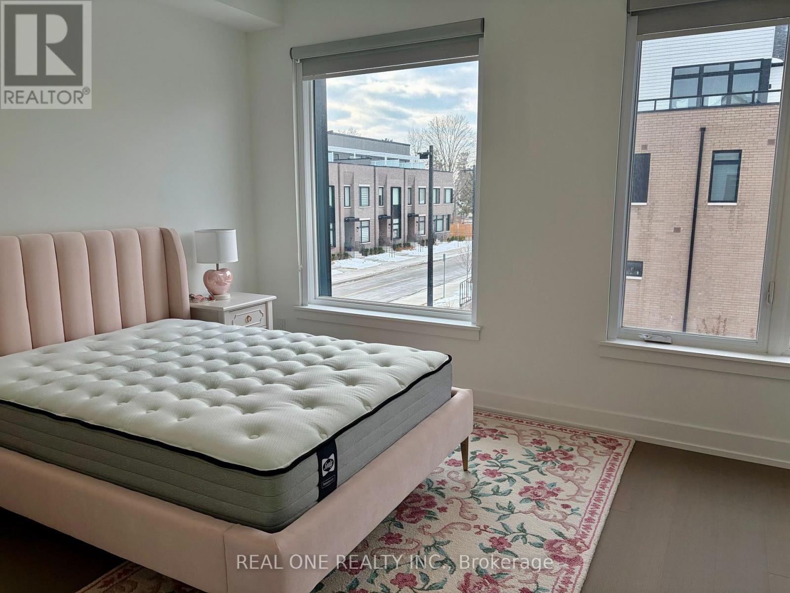 A bedroom with a large bed and a view of a street outside the window.