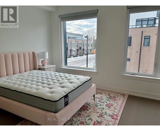 A bedroom with a large bed and a view of a street outside the window.