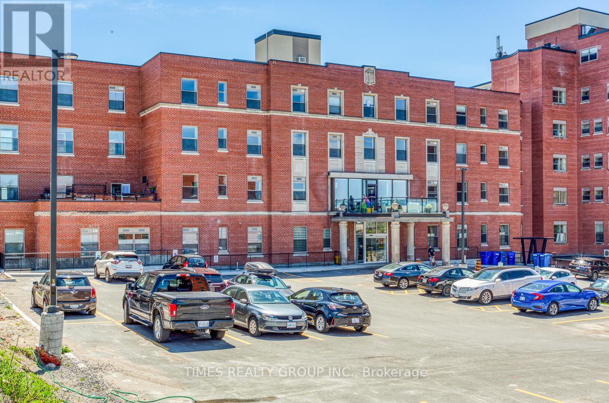 A parking lot with several cars and a red brick building in the background.