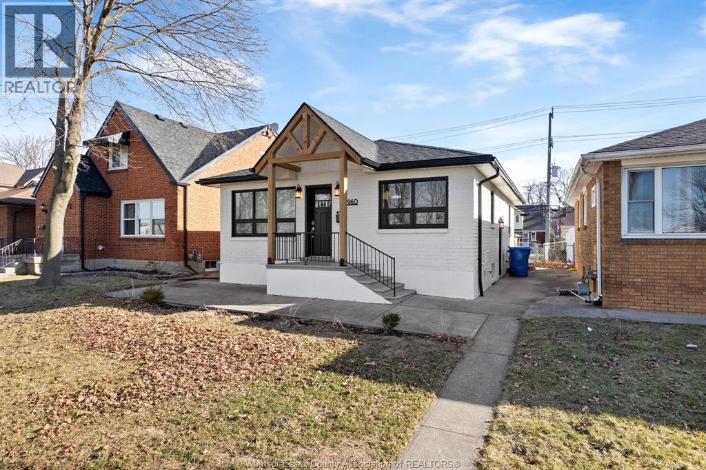 A house with a white front porch and a black roof is for sale.