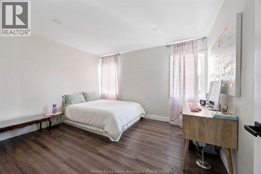 A bedroom with a bed, nightstand, and window with curtains.