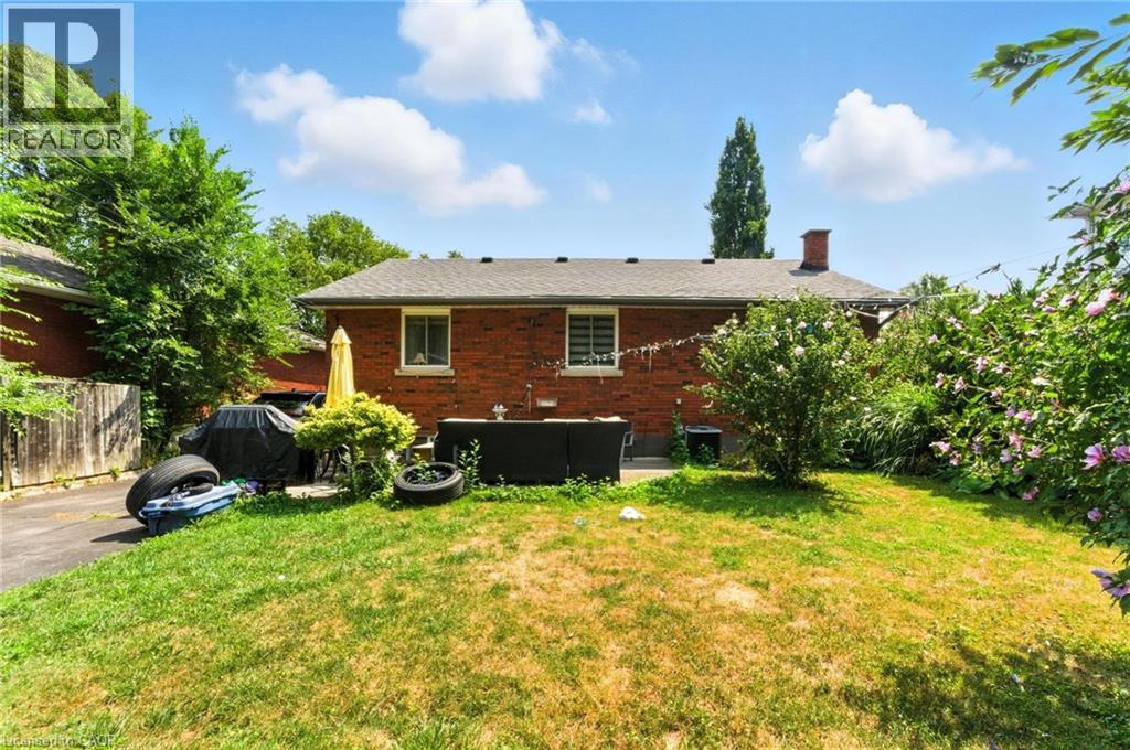 A house with a red brick exterior and a white window is surrounded by greenery.